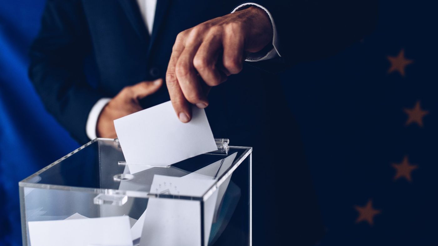Primo piano di una mano che inserisce una scheda elettorale in un'urna, simbolo delle elezioni regionali in Calabria 2025