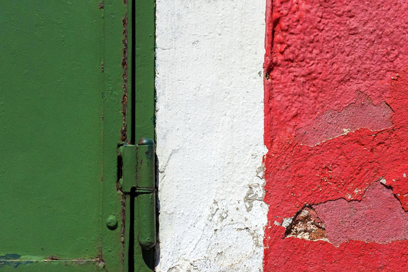 Dettaglio di una parete colorata di verde, bianco e rosso con chiusura metallica