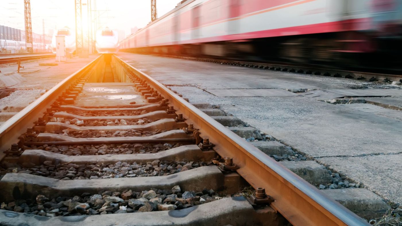 Binari ferroviari al tramonto con treni ad alta velocità in movimento