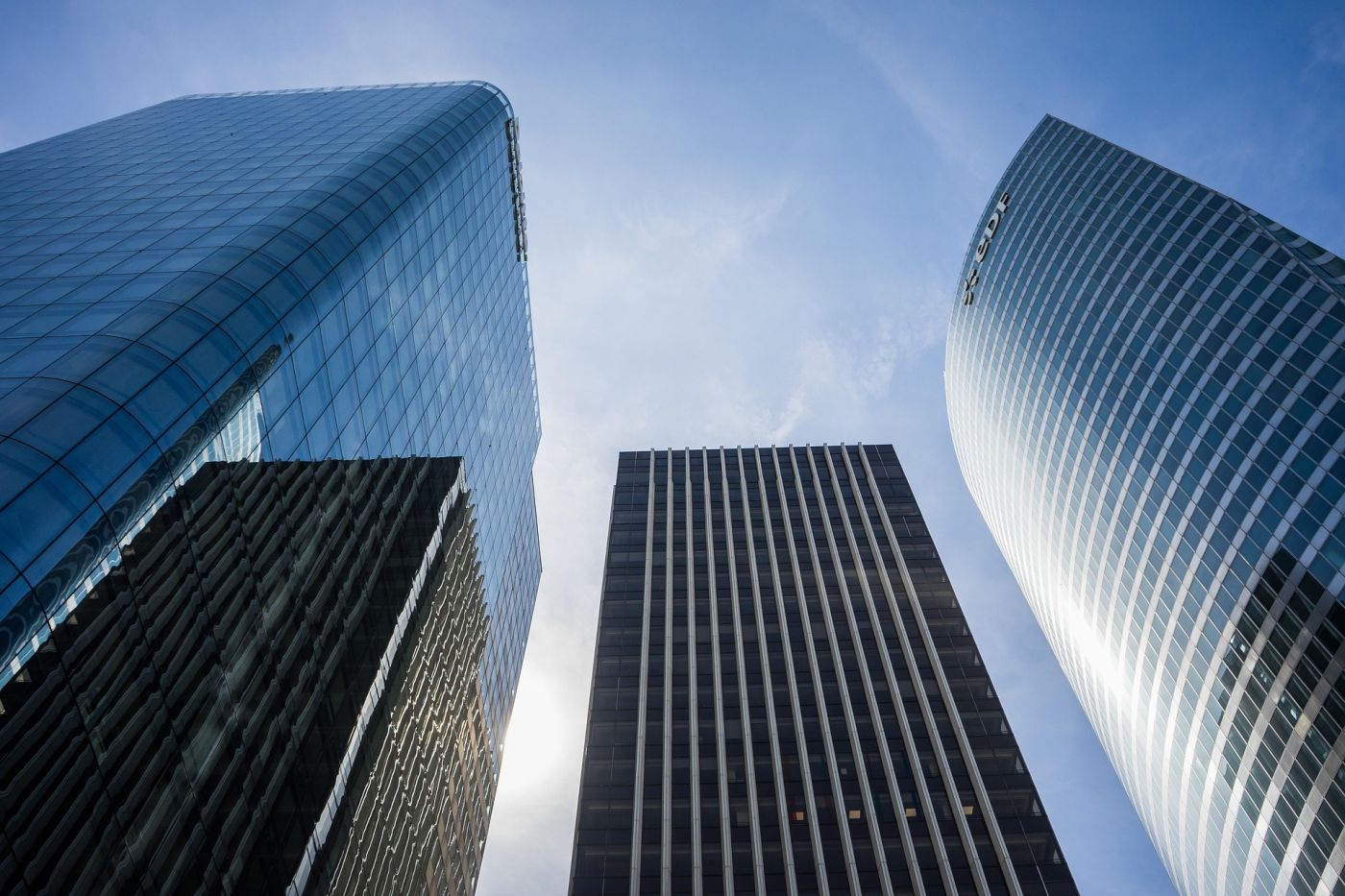 Grattacieli moderni che rappresentano la City e i centri finanziari internazionali, evocando la partenza dei miliardari da Londra verso altri paradisi fiscali.