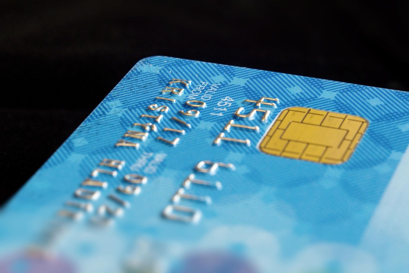 Primo piano di una carta di credito blu con chip dorato, simbolo dei capitali dei super ‑ricchi in fuga da Londra per la nuova riforma fiscale.