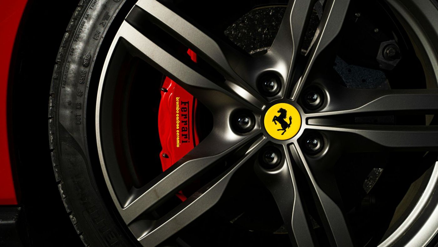 Particolare di un cerchio in lega Ferrari con pinza freno rossa e cavallino rampante