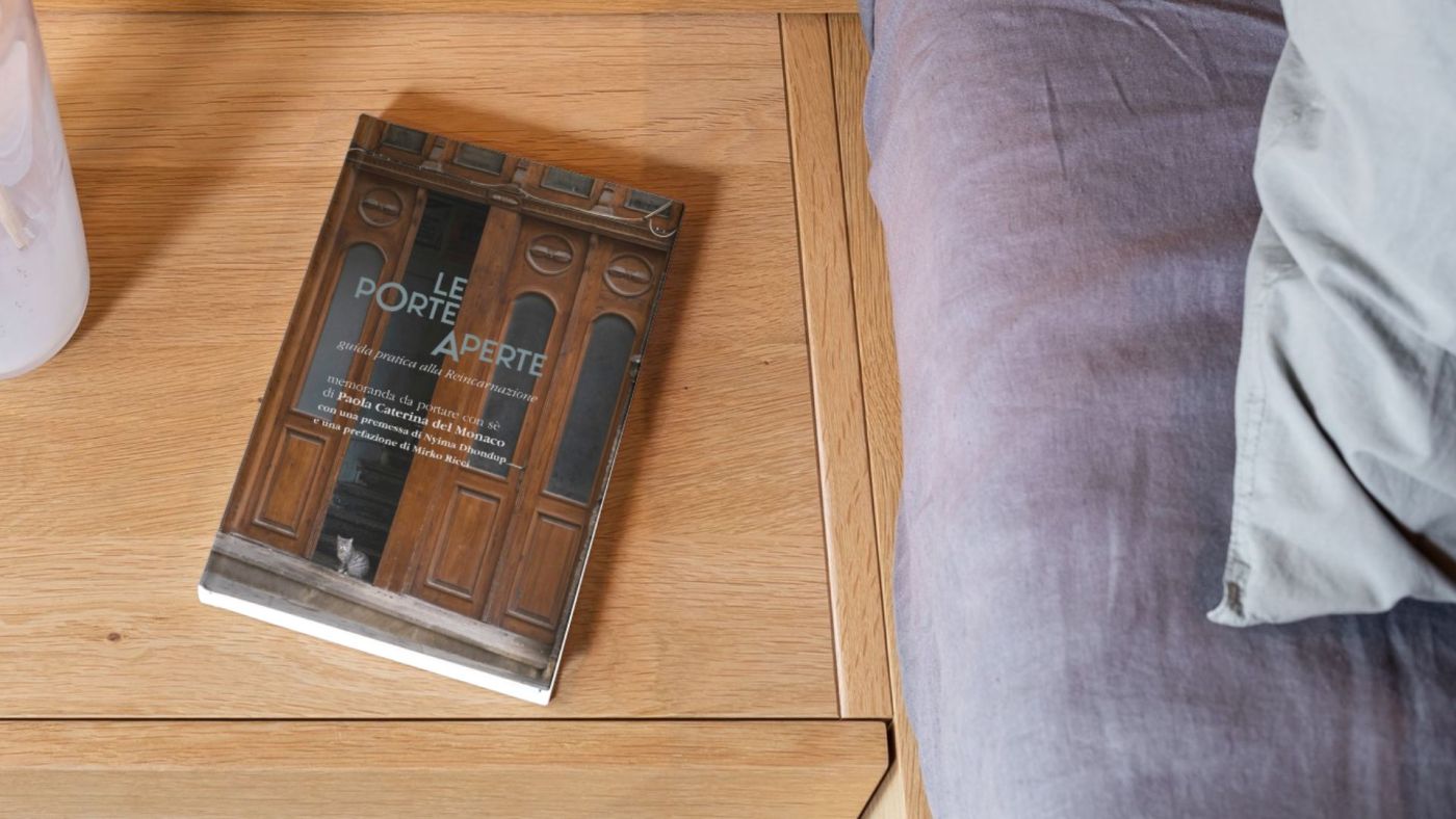Copertina del libro Le Porte Aperte su tavolino accanto a un divano