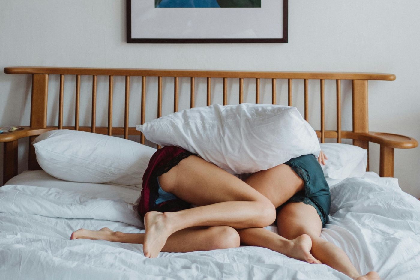Due persone sdraiate in intimo nascoste da un cuscino su un letto