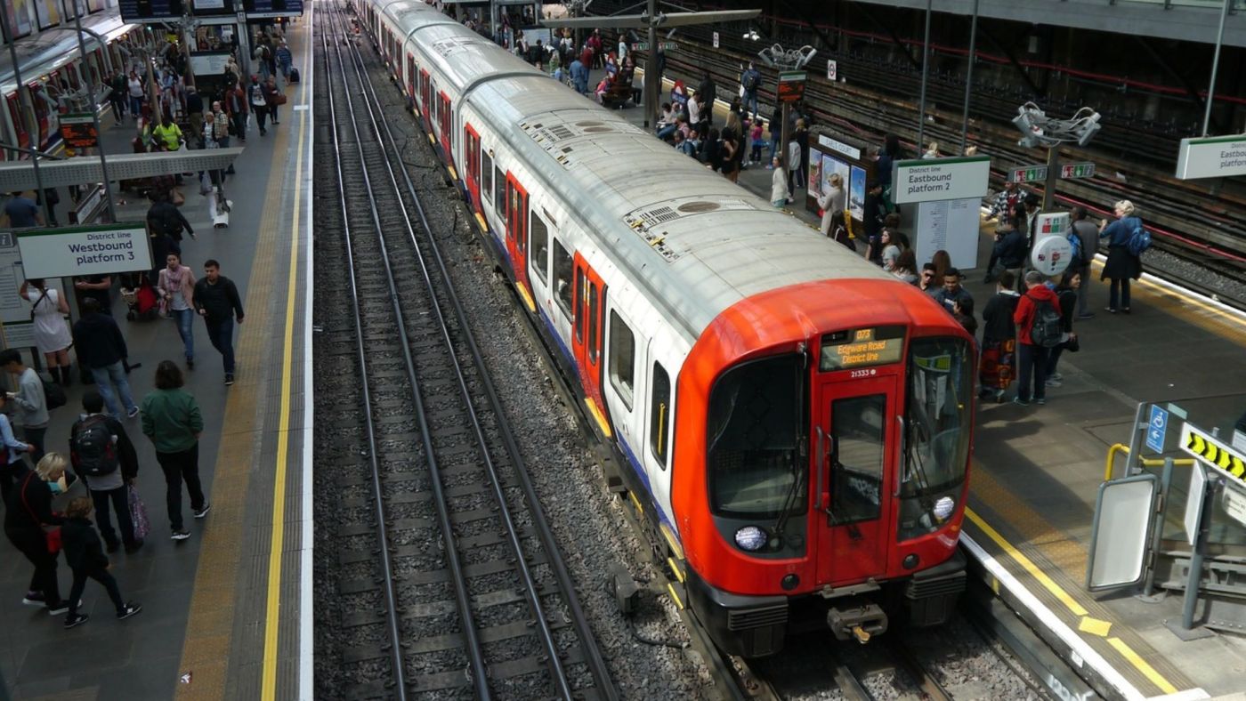 Un treno della rete ferroviaria londinese alla stazione con passeggeri in attesa