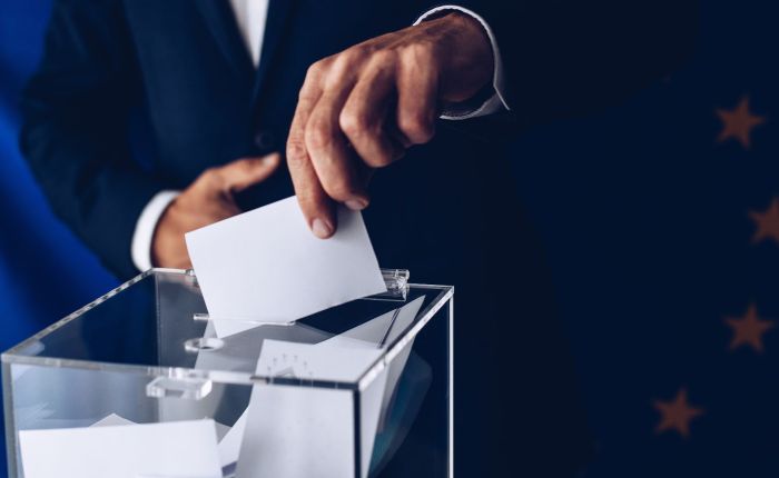 Primo piano di una mano che inserisce una scheda elettorale in un'urna, simbolo delle elezioni regionali in Calabria 2025