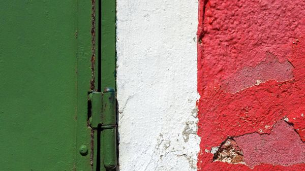 Dettaglio di una parete colorata di verde, bianco e rosso con chiusura metallica