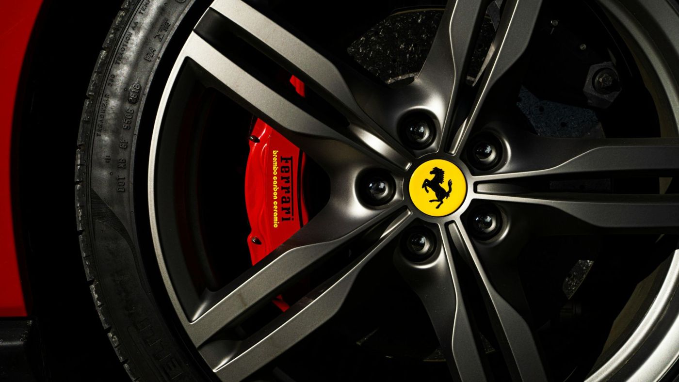 Particolare di un cerchio in lega Ferrari con pinza freno rossa e cavallino rampante