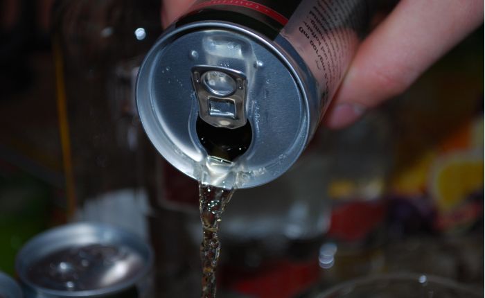 Una lattina di energy drink mentre viene versata, primo piano