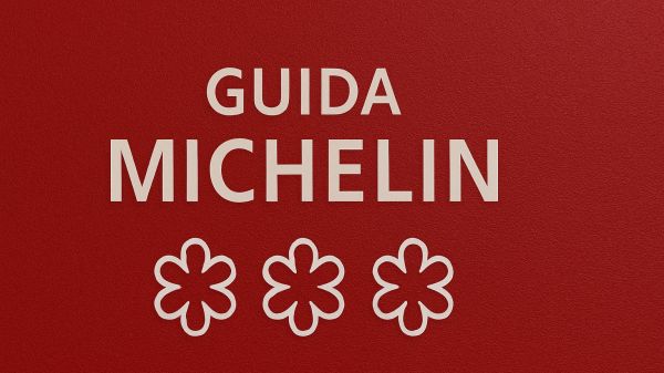 Copertina della Guida Michelin con sfondo rosso e tre stelle, simbolo della valutazione culinaria.