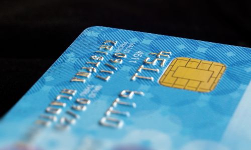 Primo piano di una carta di credito blu con chip dorato, simbolo dei capitali dei super ‑ricchi in fuga da Londra per la nuova riforma fiscale.