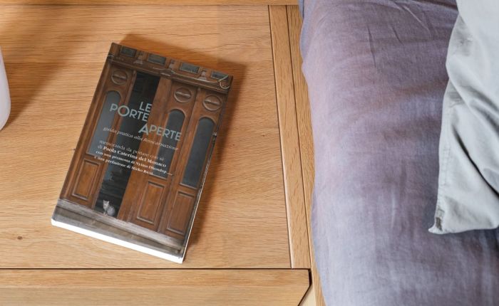 Copertina del libro Le Porte Aperte su tavolino accanto a un divano