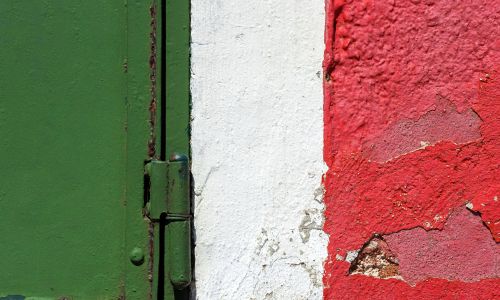 Dettaglio di una parete colorata di verde, bianco e rosso con chiusura metallica